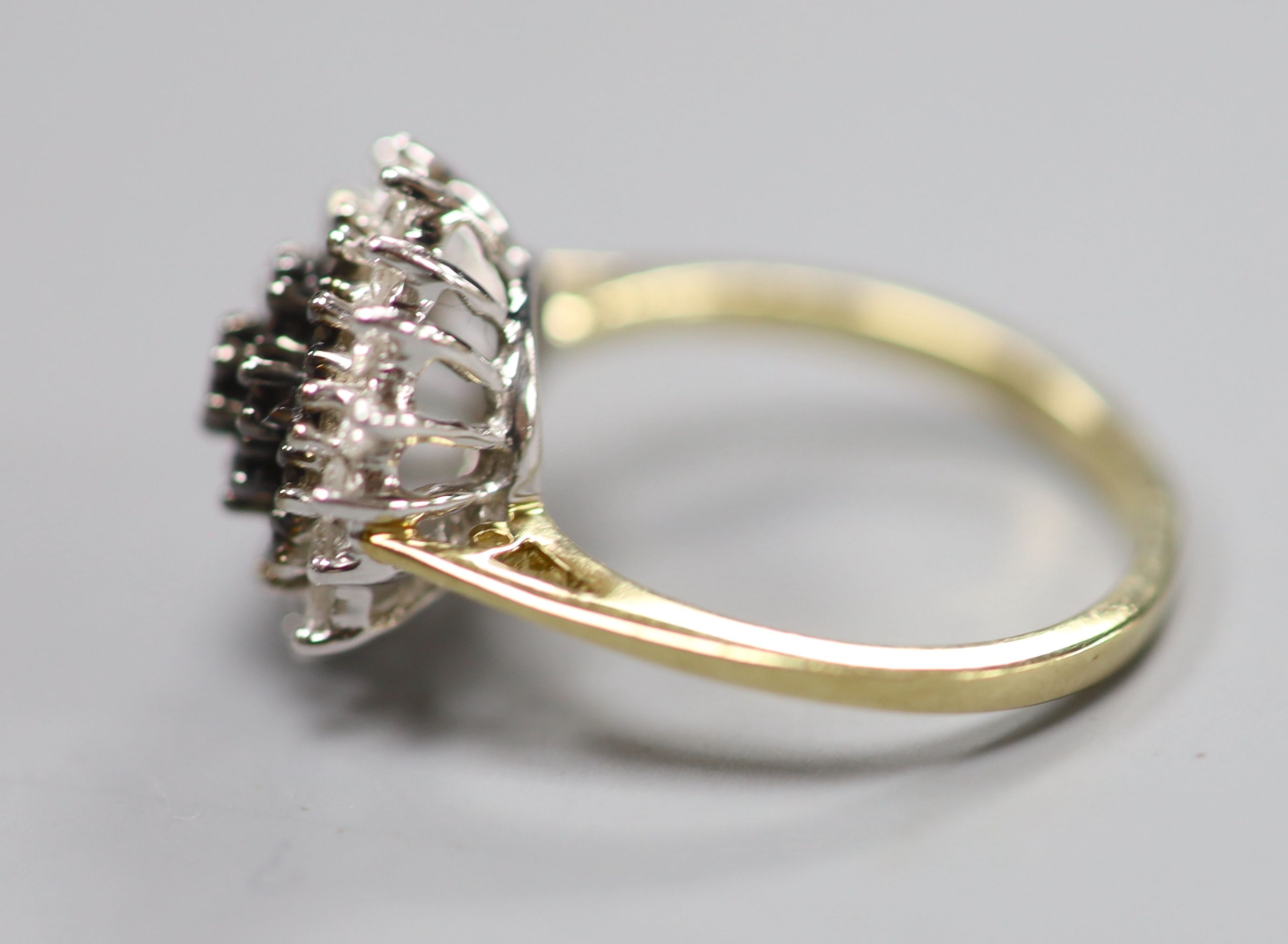 A modern 18ct gold, black and white diamond cluster set dress ring, size P, gross 4.2 grams.